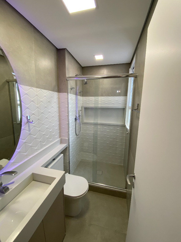 Depois: banheiro reformado com revestimento 3D, box de vidro e LED embutido